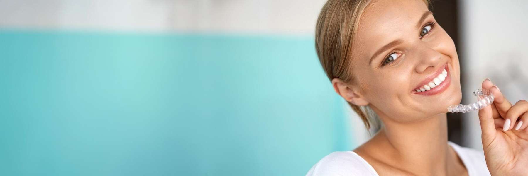 A smiling woman holding her Invisalign tray | Invisalign Allentown PA