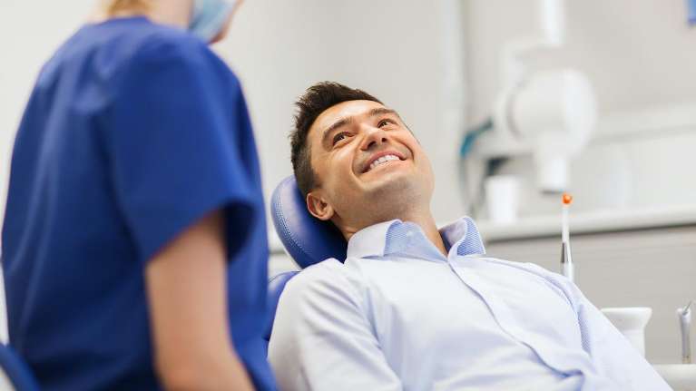 A smiling man talking to his dentist