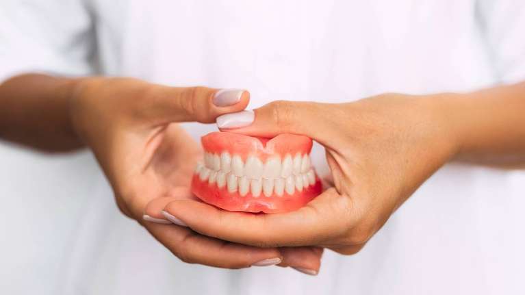 A woman holding a set of teeth | dentist Allentown, PA
