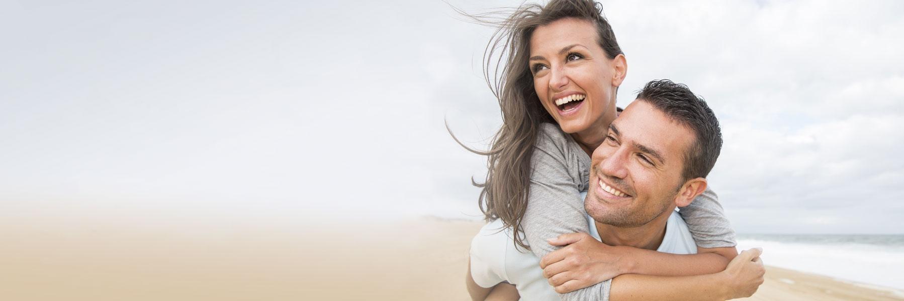 younger couple smiling on beach l gum disease treatment allentown pa